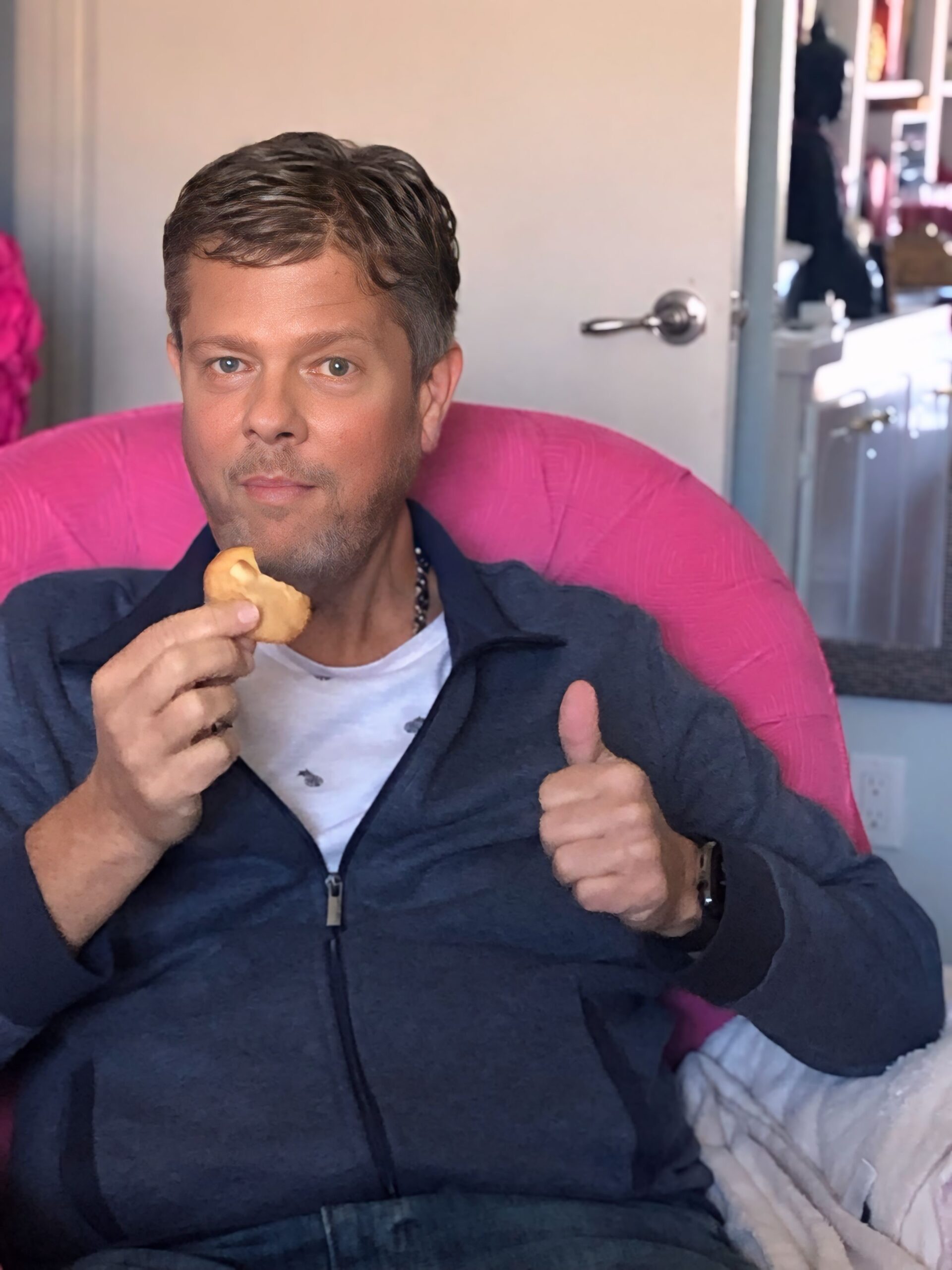Scott enjoying a low-carb white chocolate macadamia nut cookie in Kristy’s pink office chair.