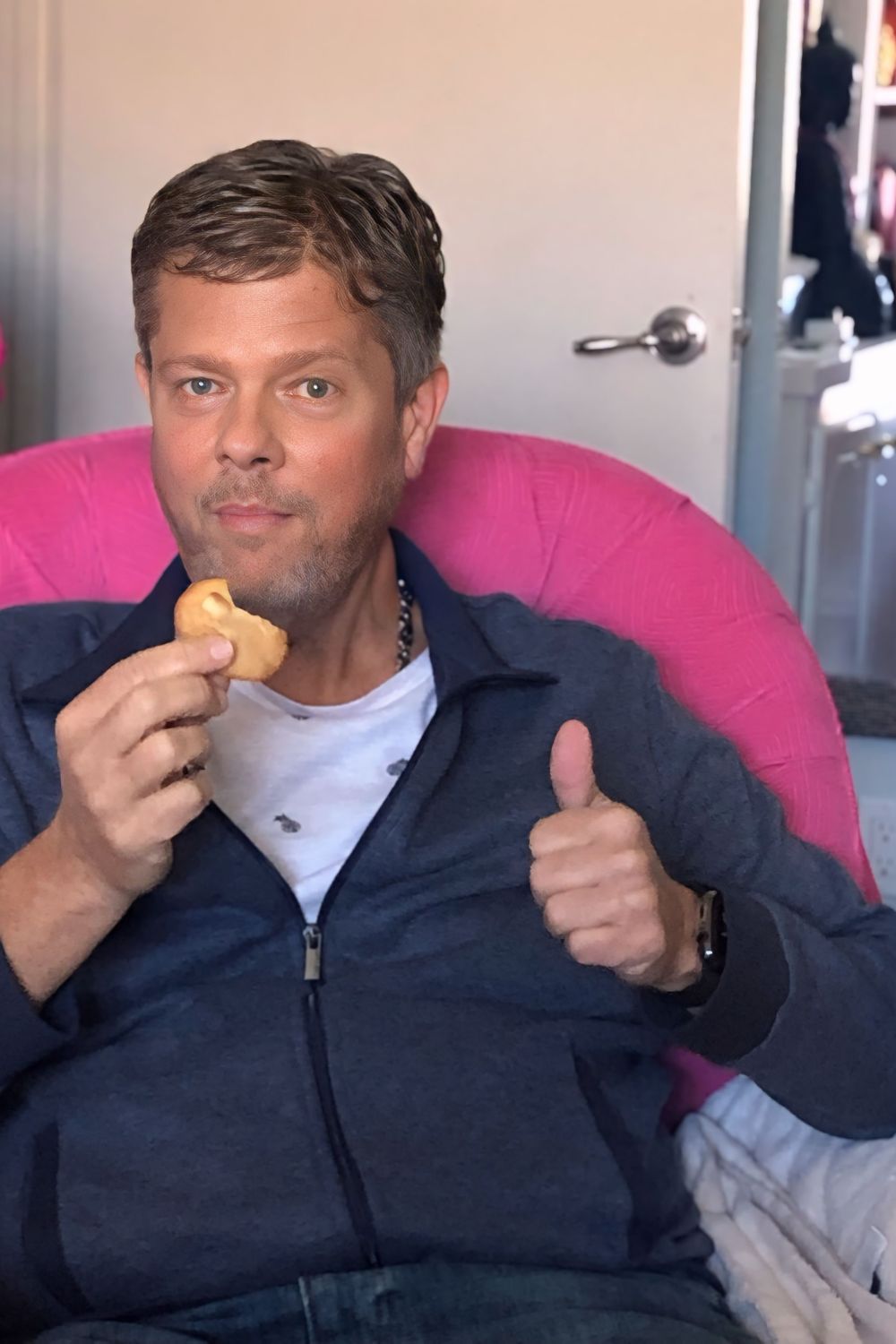 • Scott smiling while enjoying a low-carb macadamia nut cookie in Kristy’s pink office chair, six months after his diagnosis