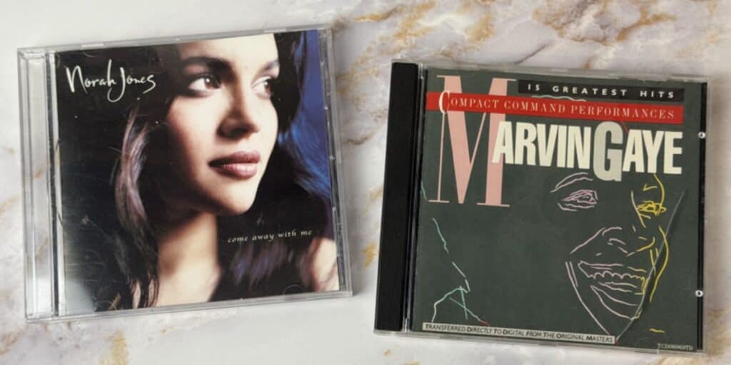 Vintage CD collection featuring Norah Jones' “Come Away With Me” and Marvin Gaye’s Greatest Hits on a marble background — music from our Joy List All-Day Playlist.